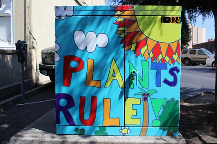 A power box painted with a sun and the words plants rule.